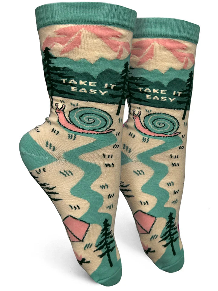 Foot forms wear tan & green crew socks featuring mountains, a tent, pine trees & a large snail forming a river trail. Text reads