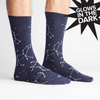 Pair of feet wears navy blue crew socks with white stars & constellations. Every few seconds the stars changed to a glow in the dark green.