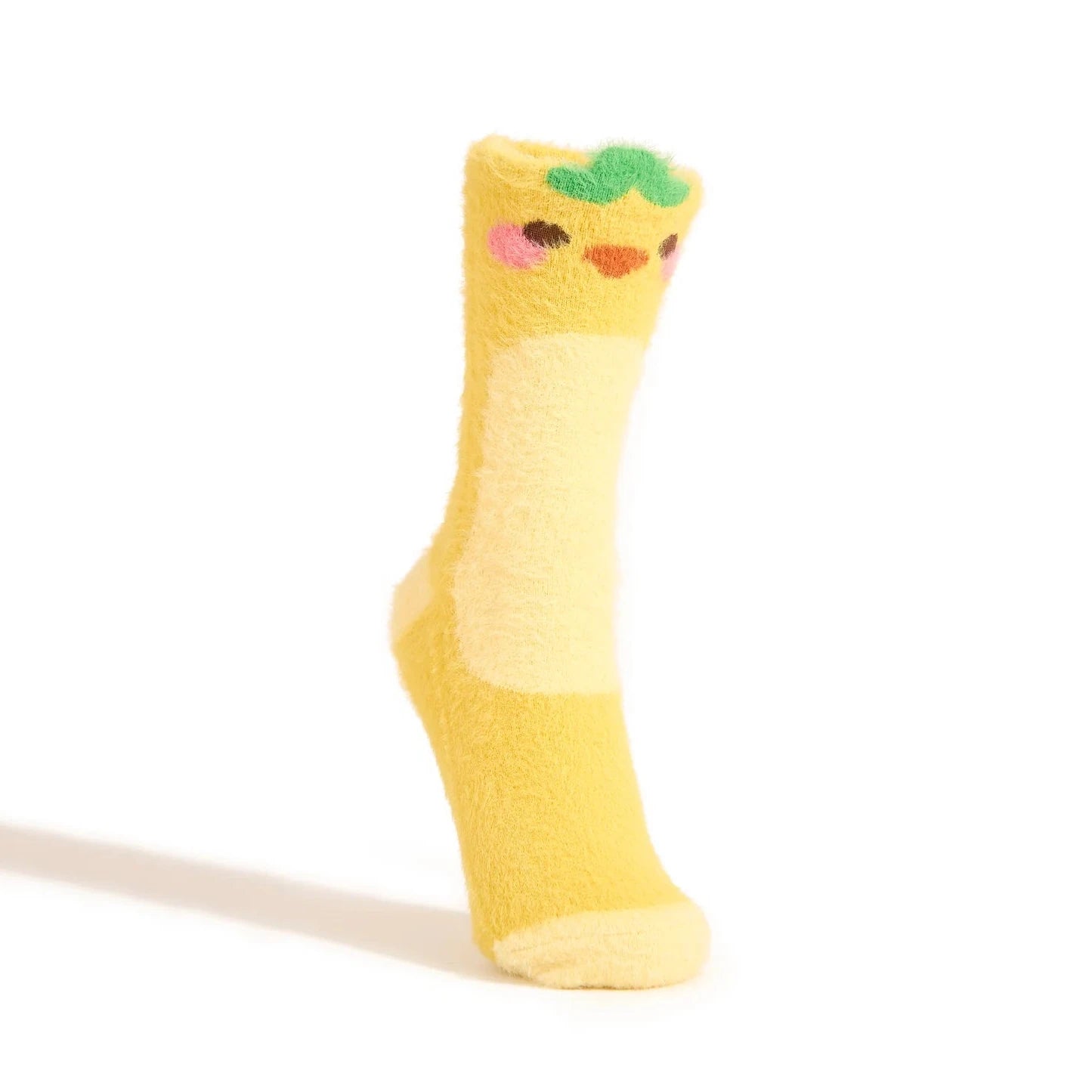 A fuzzy yellow crew sock fashioned to look like a duckling with a green leaf on its head is shown on a foot form against a white background.