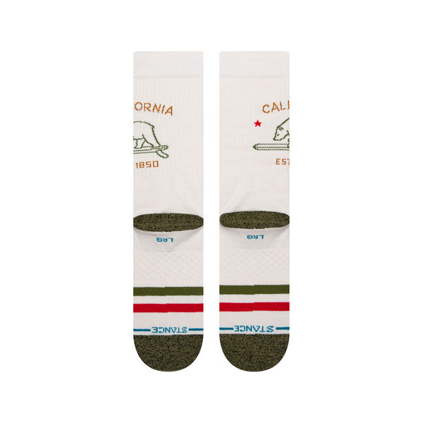 a flatlay of a pair of ivory socks with a green toe and red and green stripes on the ball of the foot with a minimal line drawing of the california bear in green with text above and below that reads california est. 1850
