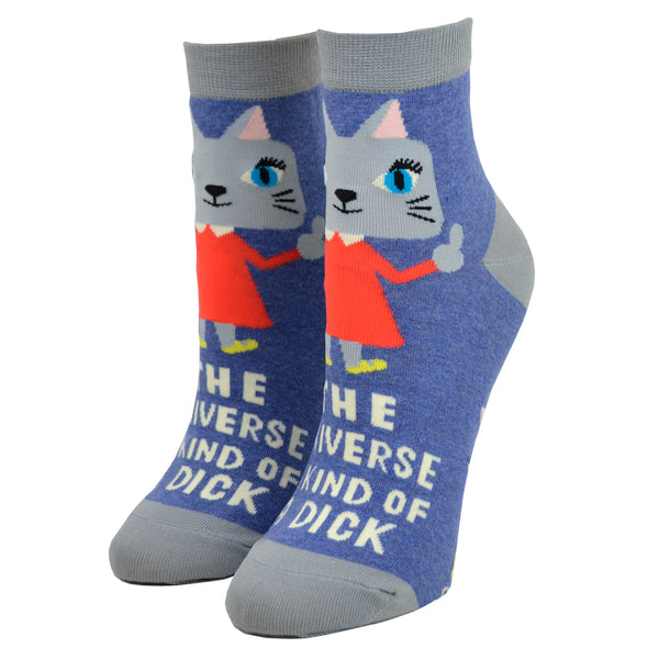 Blue ankle socks with a cat wearing an orange dress giving the middle finger and the words "the universe is kind of a dick" written, photographed from the side on a leg form.