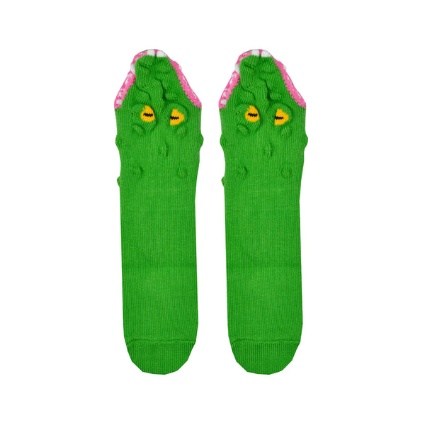 Shown in a flatlay, a pair of Foot Traffic brand cotton kids crew socks in green. The top of these socks features a fun alligator mouth design with yellow eyes, pink gums, and white teeth.