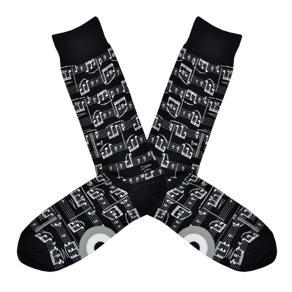 A black men's cotton crew sock by Modsock is shown on a flatlay featuring sheet music all along the sock from top to bottom.