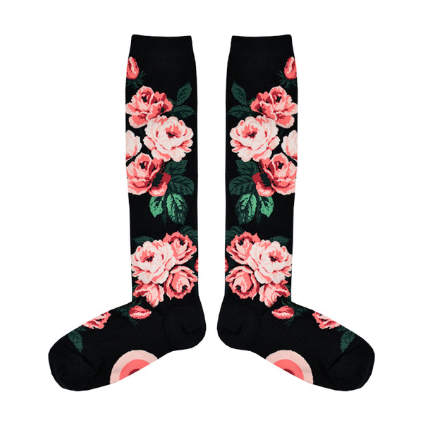 Flatlay image of black knee-high socks featuring pink roses