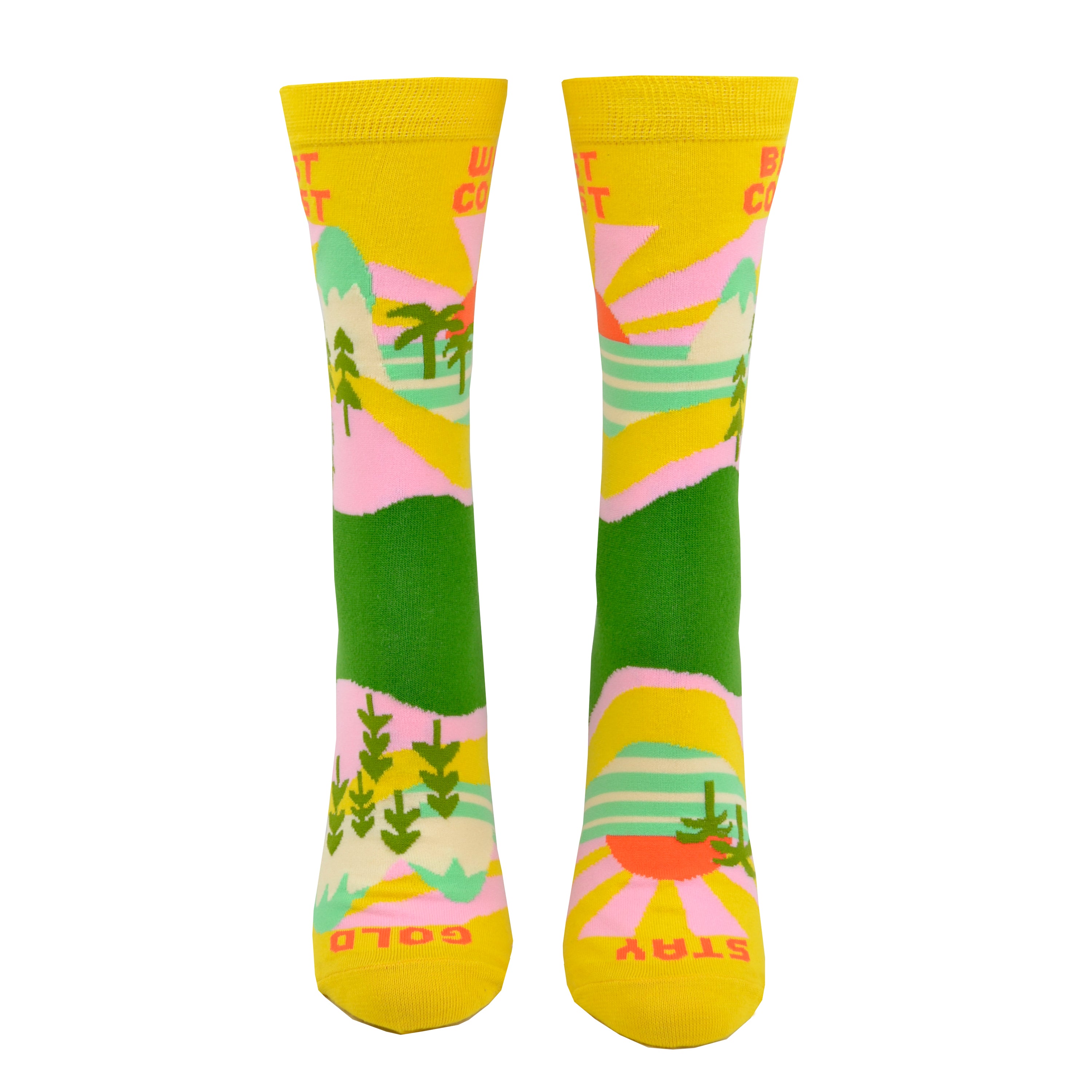 A front view on a leg form, these yellow cotton women's novelty crew socks by the brand Yellow Owl Workshop feature green trees, teal and white mountains, and pink clouds and say the words