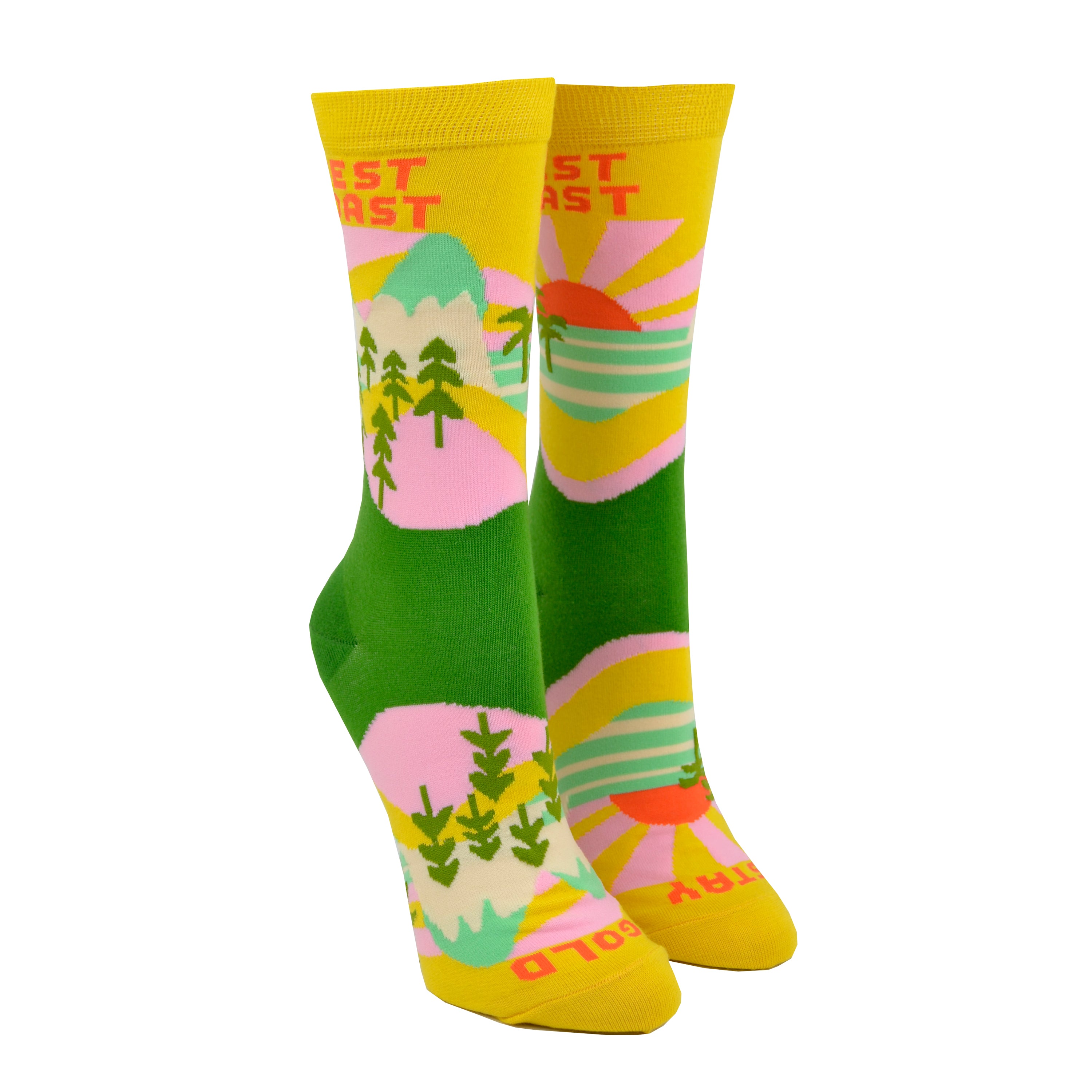 Shown on a leg form, these yellow cotton women's novelty crew socks by the brand Yellow Owl Workshop feature green trees, teal and white mountains, and pink clouds and say the words