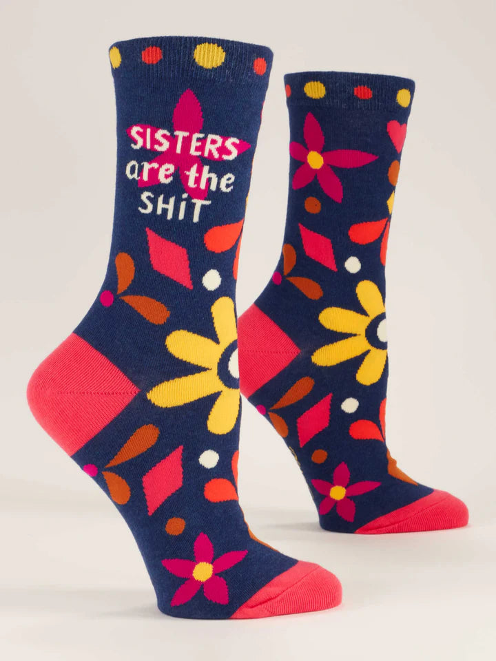 Navy blue crew socks on foot forms, with floral and geometric designs in hot pink, magenta, brown and gold with beige text that reads 