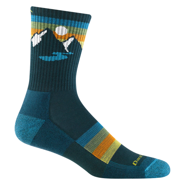 White background, quarter-crew blue hiking sock with green and orange stripes and a design with two mountains, a river and a white sun on the ankle