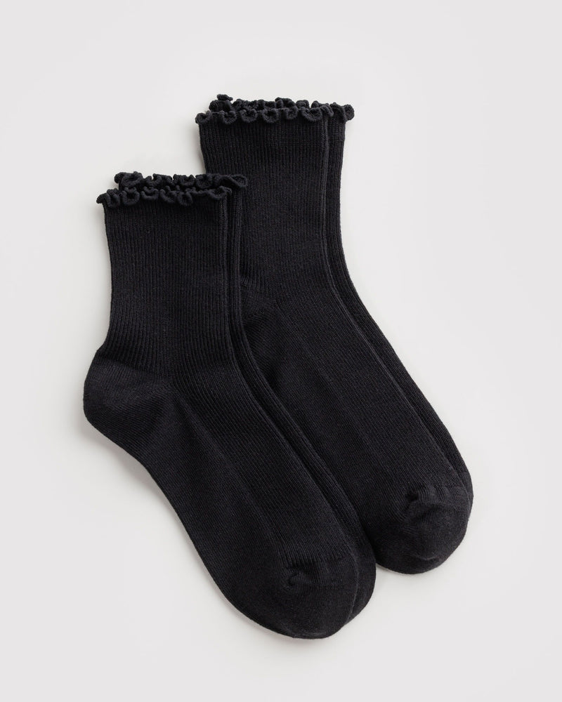 A pair of black ribbed ankle socks with matching black ruffled trim at the top, displayed on a white background.