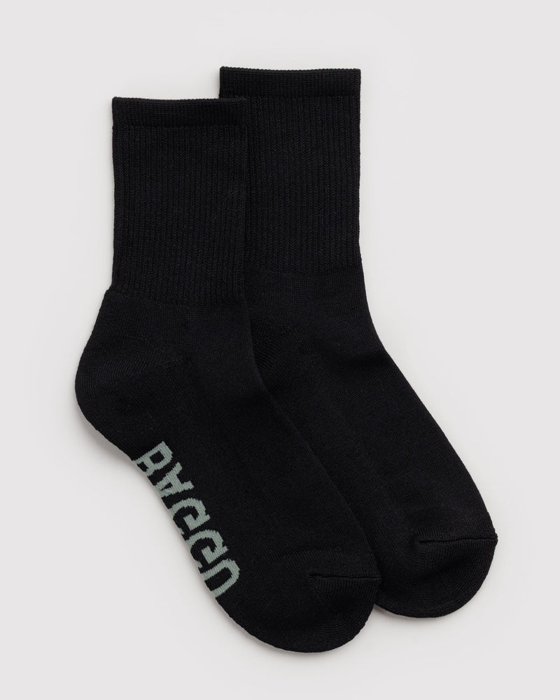 A pair of black crew socks with the brand name 'BAGGU' printed in light gray on the sole, displayed against a light gray background.