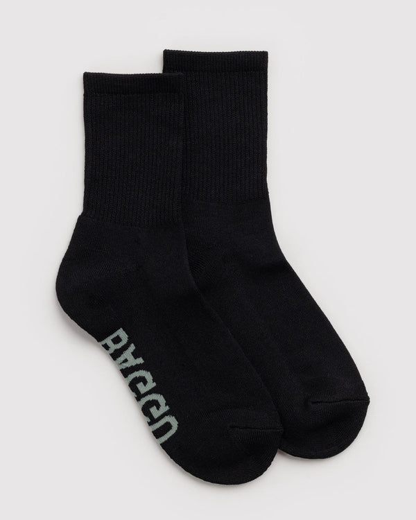 A pair of black crew socks with the brand name 'BAGGU' printed in light gray on the sole, displayed against a light gray background.