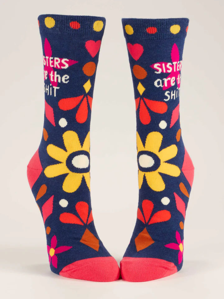 Navy blue crew socks on foot forms shown from front, with floral and geometric designs in hot pink, magenta, brown and gold with beige text that reads 