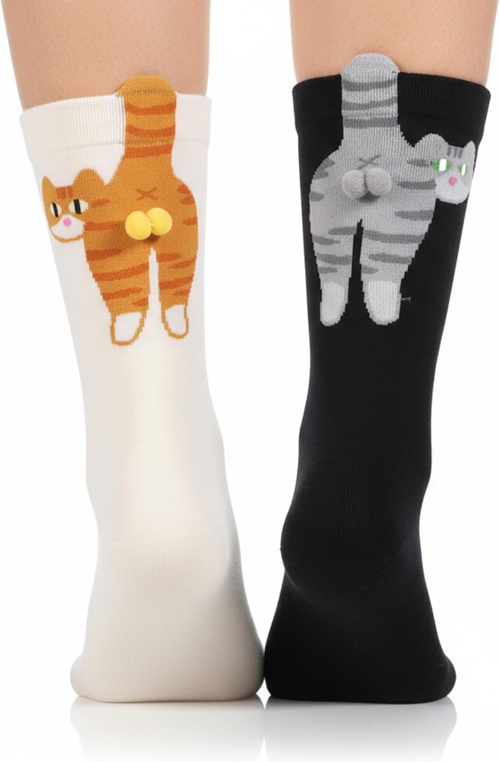 A model wears 2 socks featuring cats with pompom balls, one black with gray and one cream orange