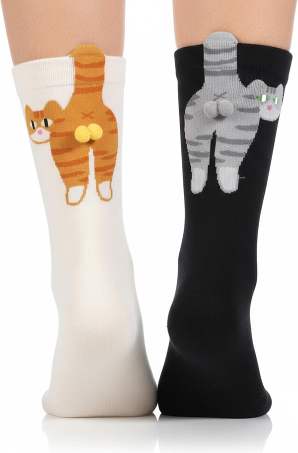 A model wears 2 socks featuring cats with pompom balls, one black with gray and one cream orange