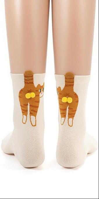 A model wears cream socks with orange cats and gold pompom balls