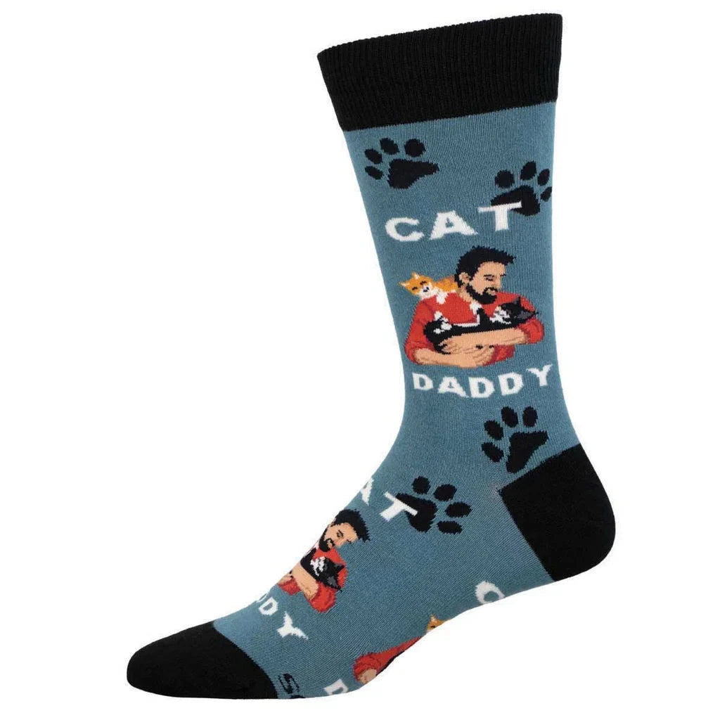 Foot form wears a blue crew sock with black heel, toe & ankle featuring black paw prints and a bearded man in a red sweater cuddling black and orange cats. White text reads 