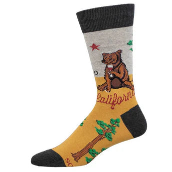 Foot form wears gray and gold crew sock with charcoal heel, toe & ankle featuring redwood trees, a grizzly bear drinking a glass of red wine, a red star, red script that reads 