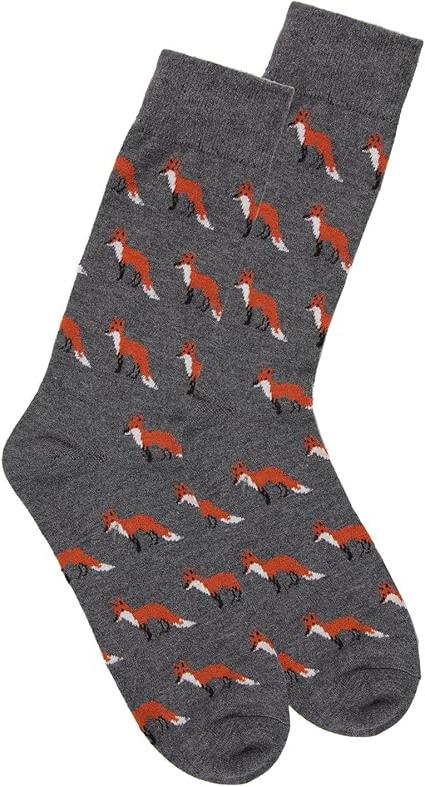 A white background shows a pair of charcoal-colored crew socks in flatlay. Orange foxes in a standing position repeat across the sock in a tessellated style.