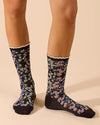 Black floral socks with lace trim worn by a model shown knees-down