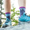 Model wears hiking shoes and blue/purple socks featuring a bear and a treeline