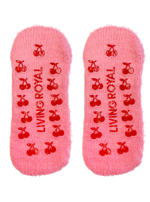 a pair of pink slipper socks displaying their soles, which are covered in plastic non-skid grips shaped like cherries and the text LIVING ROYAL