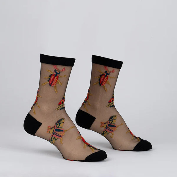 Sheer socks on foot forms with  black edges and red & yellow embroidered beetles