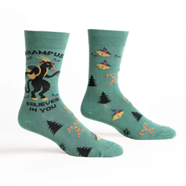 Teal socks with Krampus and holiday motifs. Text reads 