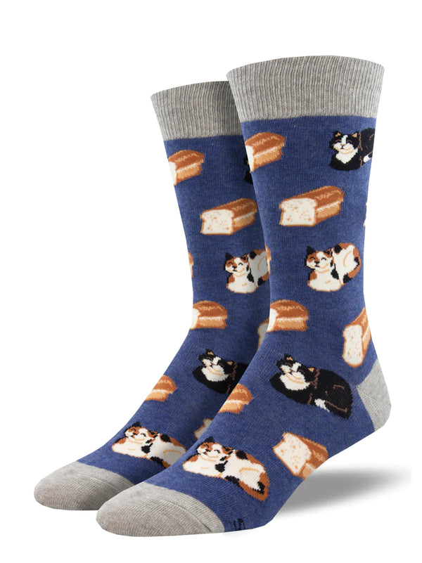 Shown on leg forms, a pair of Men's cotton crew socks in blue with a gray heel, toe, and, cuff. These socks feature cats in loaf formation and loaves of bread. 