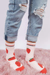 Person wearing ripped jeans and strawberry-patterned socks on a pink carpet