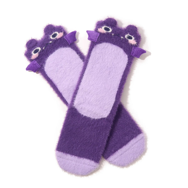 A pair of purple fuzzy crew socks with blushing bat faces and 3D wings at the top are shown in flatlay on a white background.