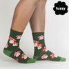 a pair of tan legs wearing green socks featuring red and pink mushrooms with little happy faces and pink cheeks