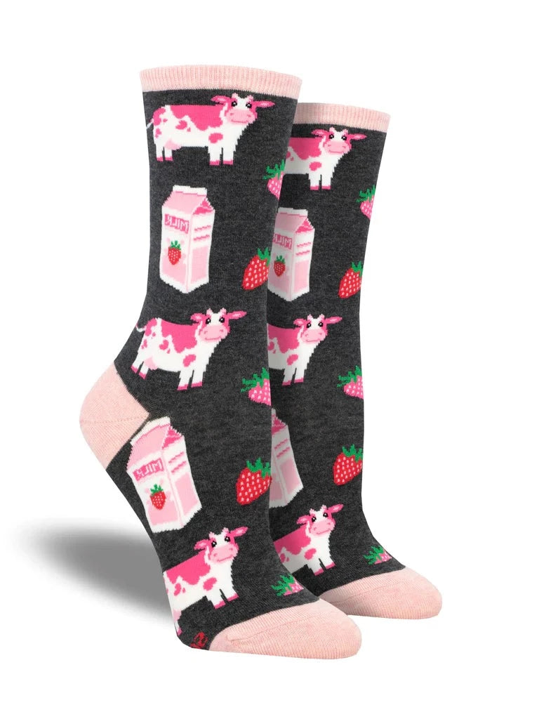 Shown on leg forms, a pair of women's cotton crew socks in dark gray with a peach heel, toe, and, cuff. These socks have pink cows, strawberries, and, strawberry milk cartons all over. 
