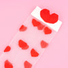 Red heart-shaped objects on a clear plastic sheet against a pink background
