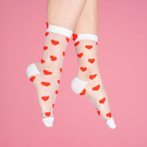 Sheer socks with red heart patterns on a pink background