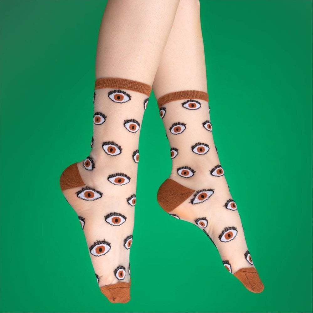 a pair of feet wearing sheer socks covered in a motif of brown eyes with a brown toe heel and cuff