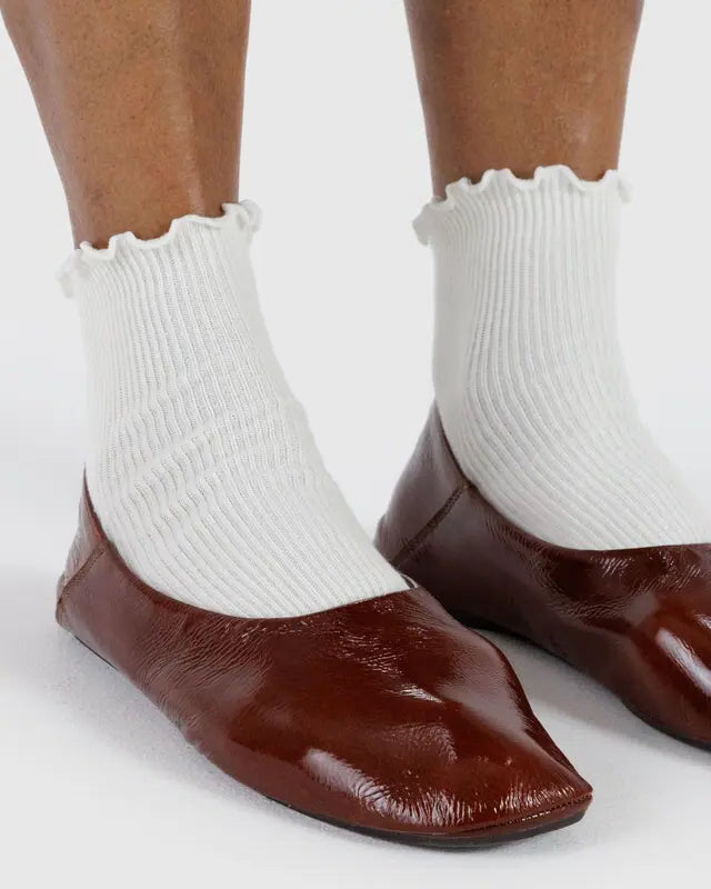 Model wears white ankle socks with a lettuce edge and brown loafers