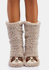 Model wears beige sherpa slipper socks with sloth faces
