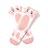 Two white socks with large pink splotches and 3D cow faces sit in flatlay against a white background.