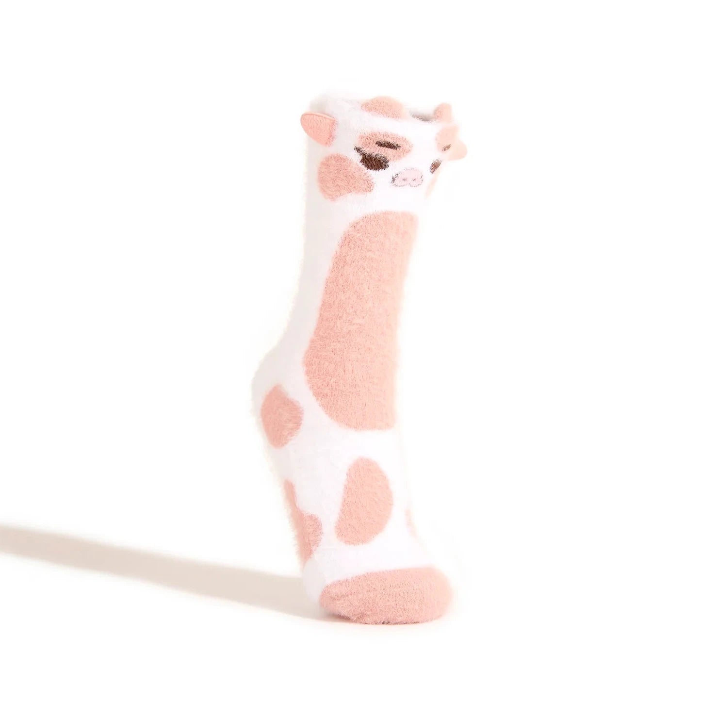 A single fuzzy white sock with pink spots and a 3D cow face sits on a footform against a white background.