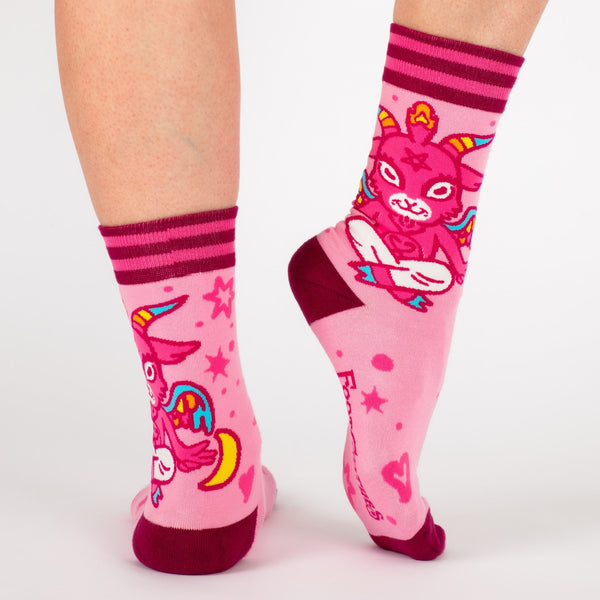 Shown on a model's legs from the side and back, the pink Cute Baphomet crew socks by Foot Clothes.