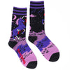 Shown in a flatlay, a pair of purple and black unisex crew socks with a black heel and toe. The cuff is stripped purple and black while the leg of the sock features an evil bleeding unicorn with lightning behind them. The foot is light and dark purple.  