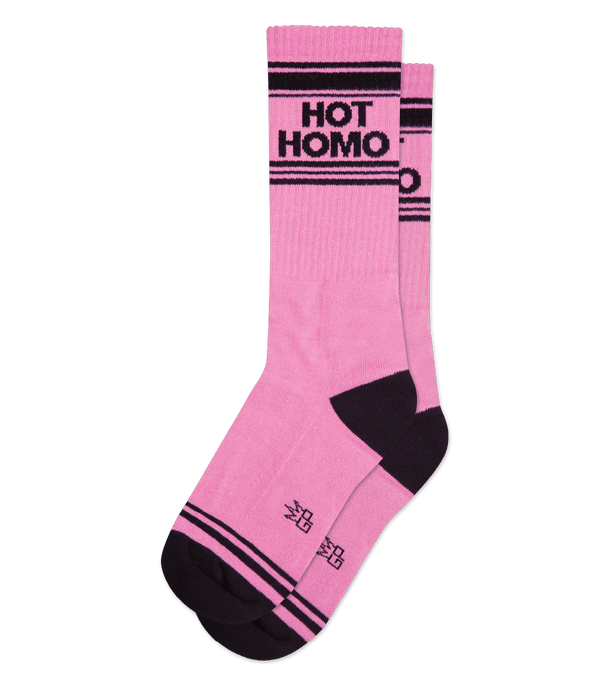 Shown laid flat, a pair of pink cotton Gumball Poodle brand unisex crew socks with black striped toe and cuff. These socks feature the words, "HOT HOMO" on the leg in black.