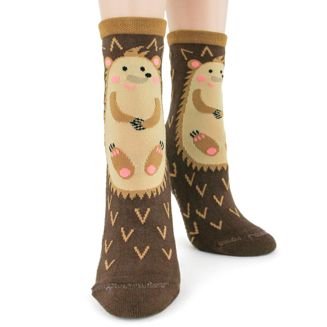 Shown on a model, a pair of women's cotton crew lounge socks by Foot Traffic. These socks are an all over brown with a hedge hog cartoon on the front and they feature a non-skid sole.