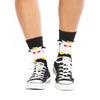 Shown on a model wearing Converse sneakers, a pair of Foot Traffic, black and white cotton women's crew socks with three dimensional pattern of cute penguin