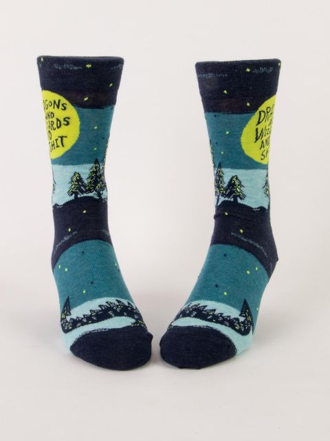 A pair of blue socks on foot forms featuring pine trees, a spiky dragons tail, and the text inside a lime green circle that says 