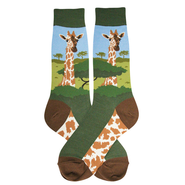 Shown in an artistic flatlay, a pair of Foot Traffic green cotton men's crew socks with a giraffe and acacia trees