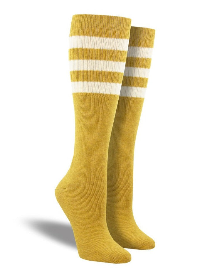 Shown on a leg form, these heathered mustard cotton unisex tall crew socks by the brand Socksmith have 3 white horizontal stripes hugging the calf.