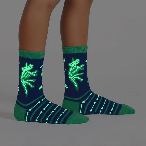 dinosaur fossil socks glowing in dim lighting on a child's feet