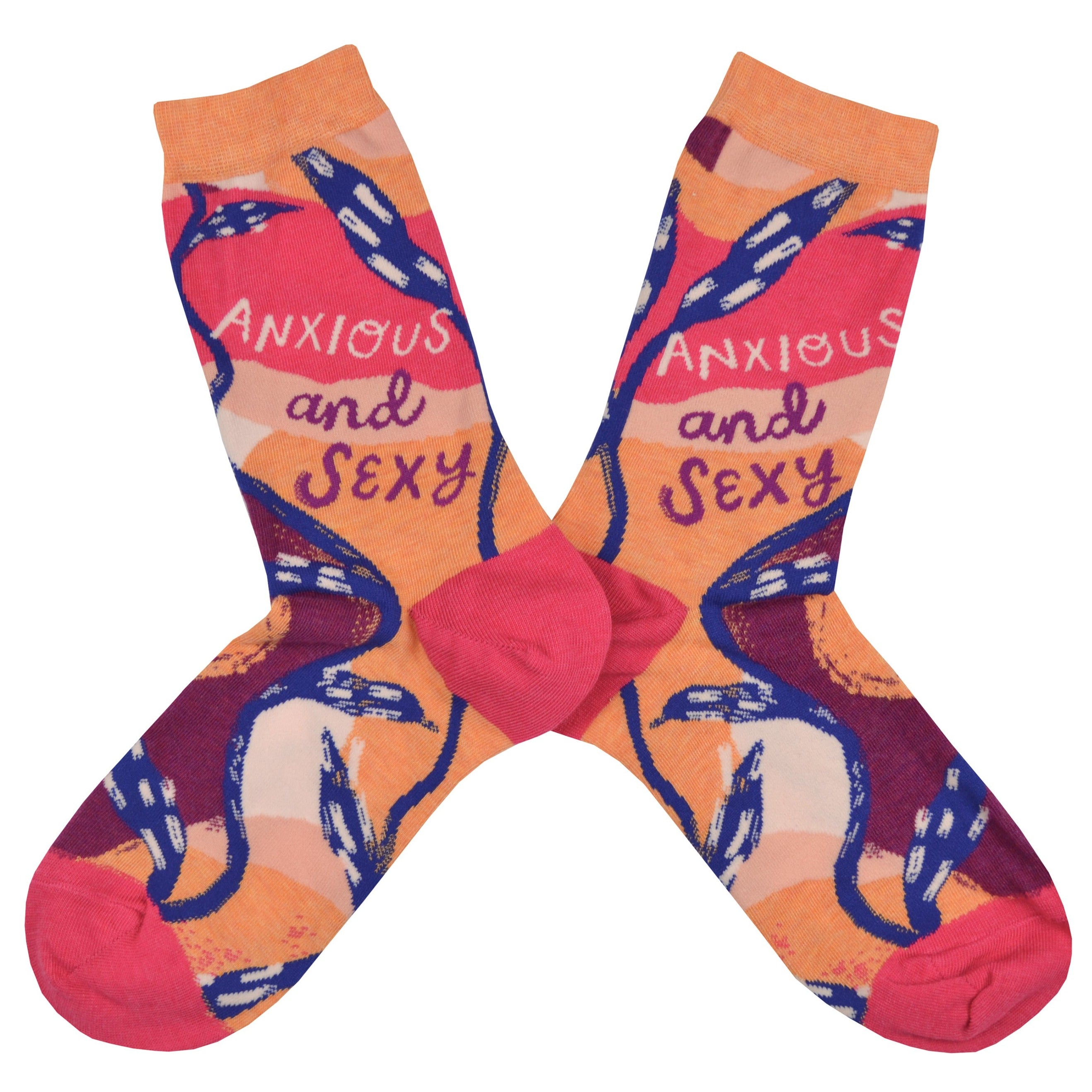 Shown in a flatlay, a pair of Blue Q brand women's cotton crew socks with a hot pink heel and toe with an orange cuff. The sock has an abstract design of hot pink, light pink, orange, and purple with a blue vine weaving around the sock. On the leg in a cursive font the sock reads, 