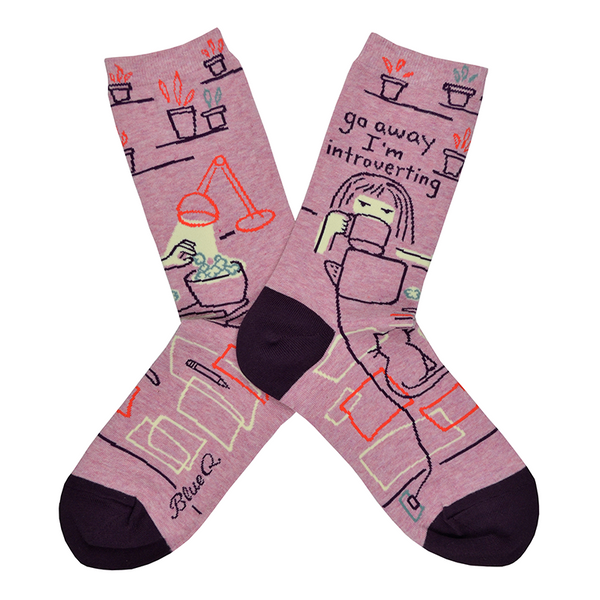 A girl is seen at her desk eating popcorn and watching her laptop with the words "Go away I'm introverting" written above her on the leg of this crew length women's cotton sock by Blue Q.